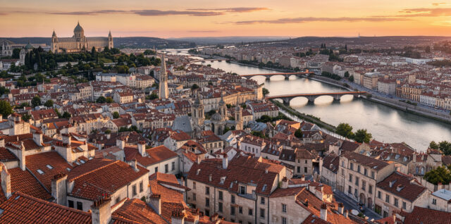 Vue panoramique lumineuse de Lyon depuis Fourvière, avec ses toits historiques, le Rhône, la Saône et ses monuments au coucher du soleil.
